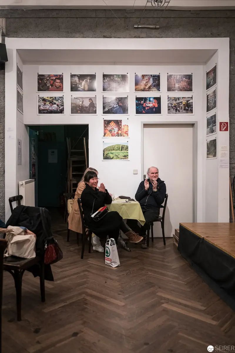 Gallery Interior with Two Seated Visitors Amid Photographic Exhibition