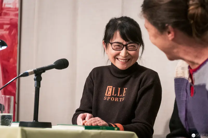 Elle Sports Presenter Smiling During Panel Discussion with Microphone