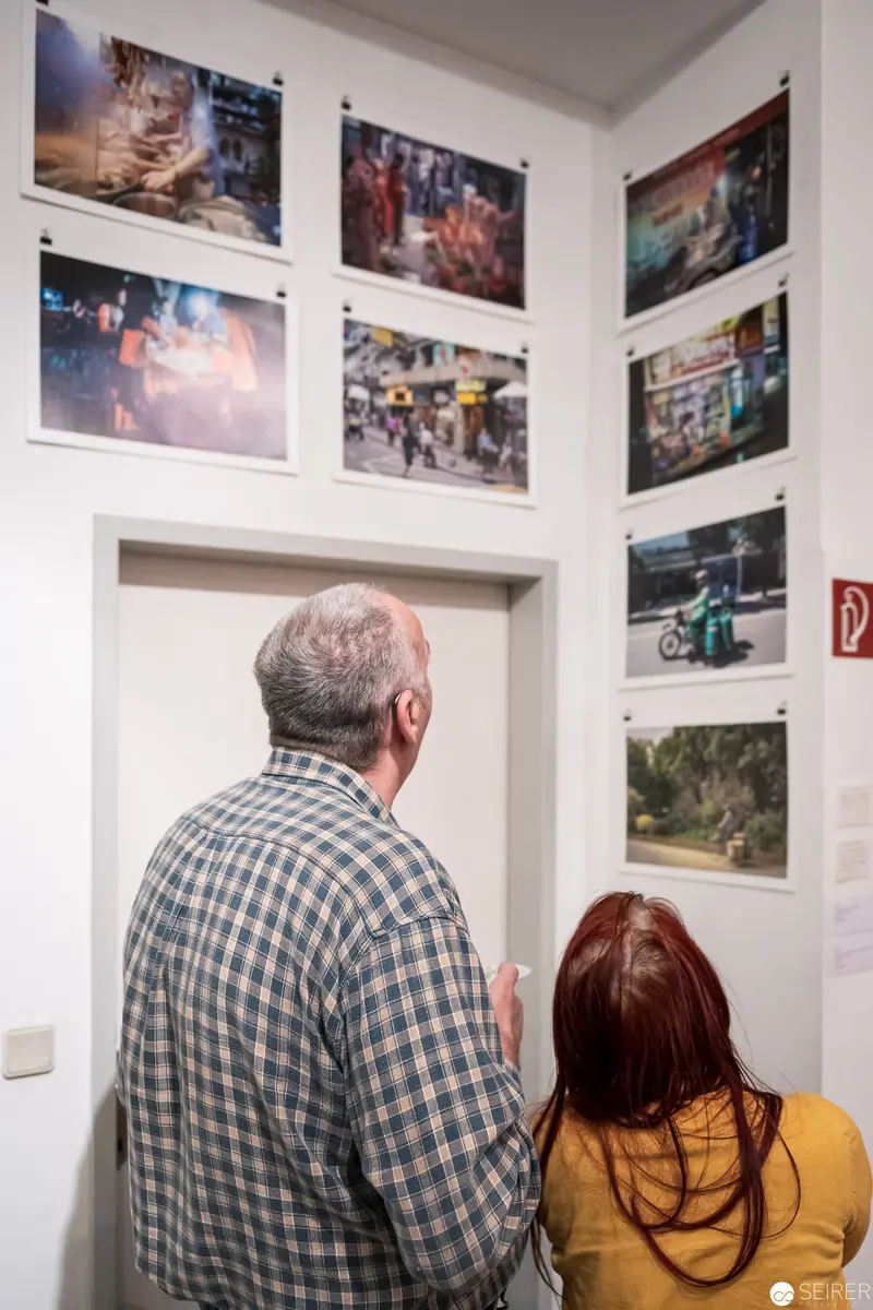 Gallery Visitors Examining Contemporary Photographic Exhibition Wall Display