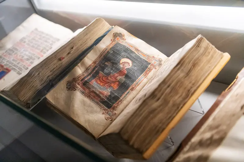 Medieval Illuminated Manuscript Open to Decorative Page Under Museum Lighting
