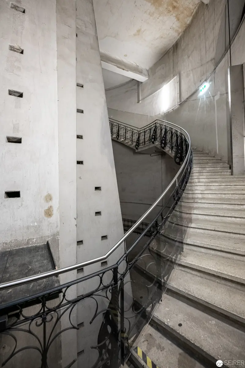 Curved Concrete Staircase with Ornate Metalwork in Minimalist Interior