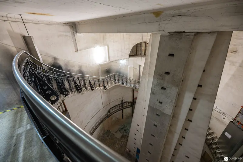 Curving Staircase in Concrete Interior with Ornate Metal Railing