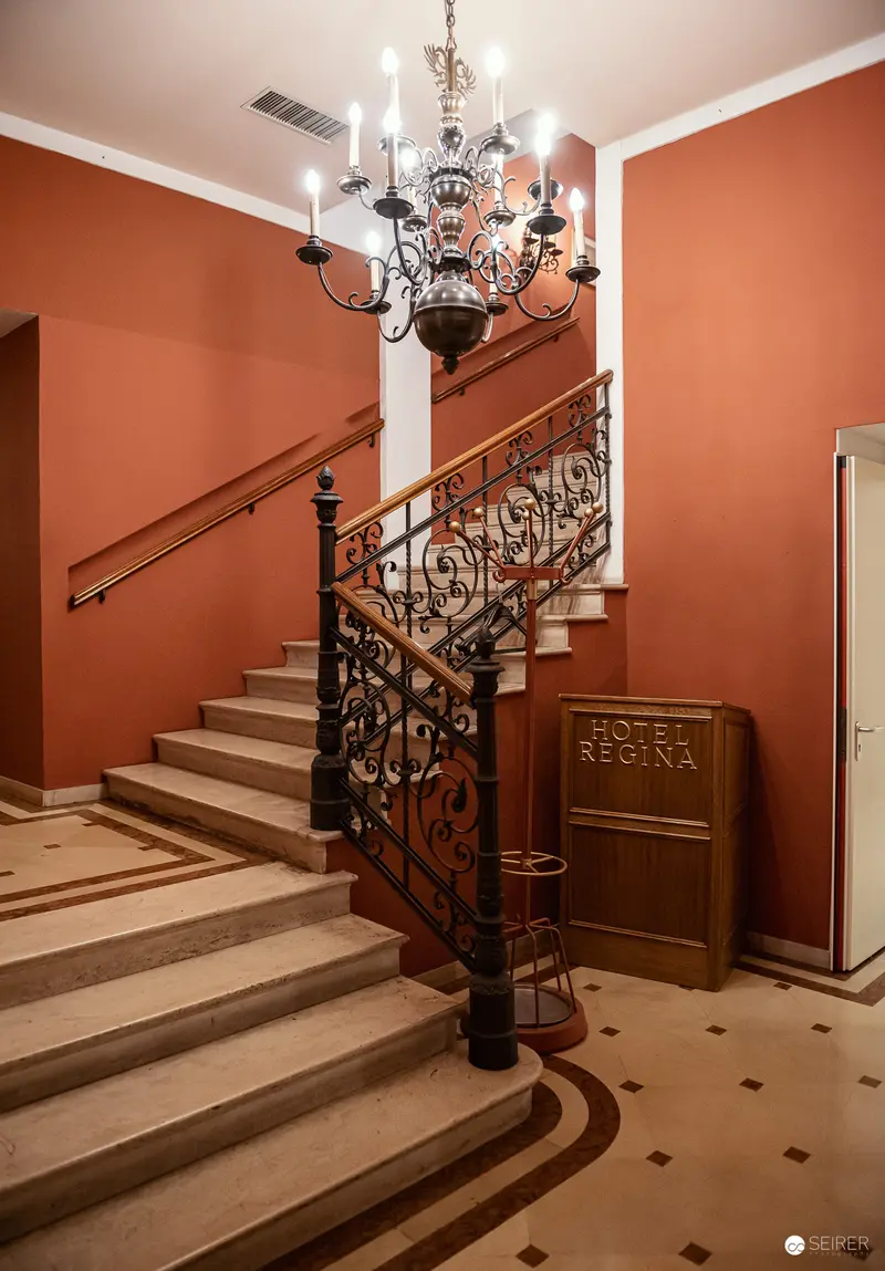 Elegant Staircase Interior at Hotel Regina with Ornate Chandelier and Wrought-Iron Balustrade