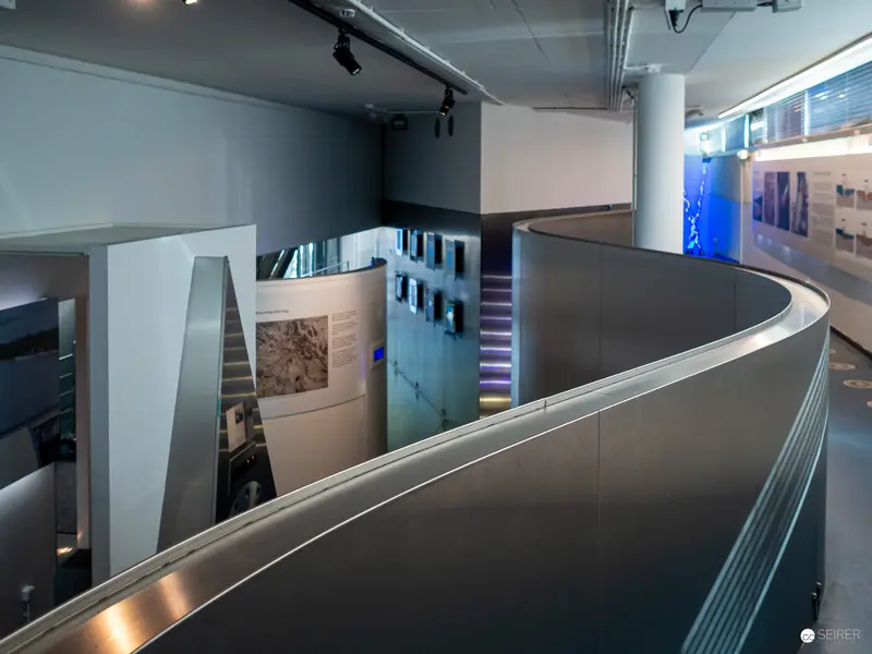 Curved Metallic Gallery Walkway with Exhibition Panels and Digital Display