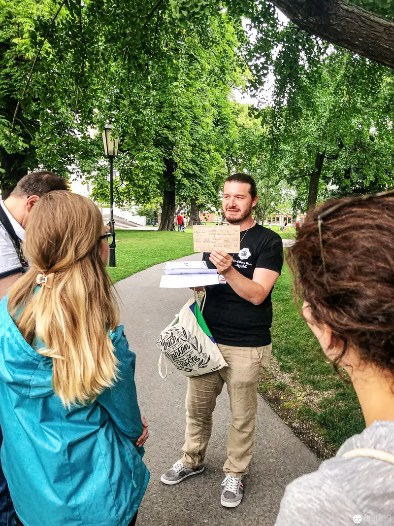 Instructor Lecturing Outdoors to Small Group on Paved Park Pathway