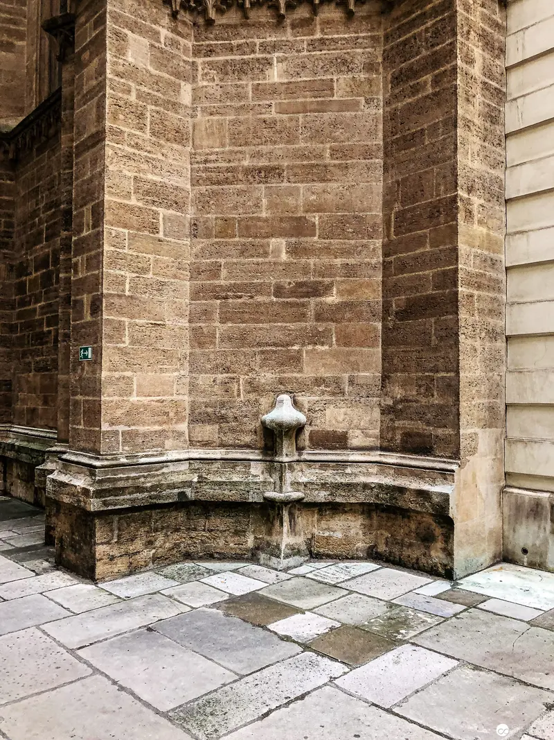 Stone Corner Fountain with Aged Masonry Wall and Geometric Paved Floor