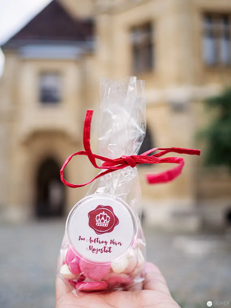 Hand-Held Packaged Sweet Treat with Red Ribbon Against Blurred Urban Background