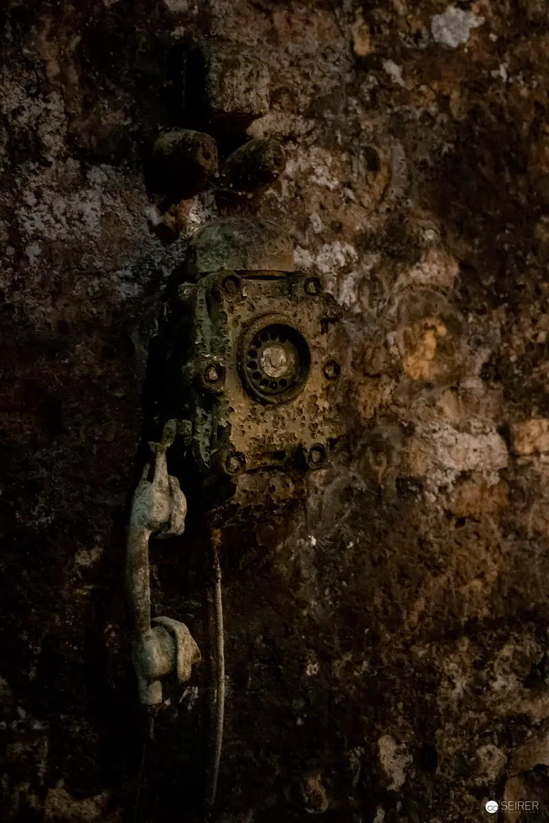 Antique Corroded Rotary Telephone on Weathered Stone Wall Surface