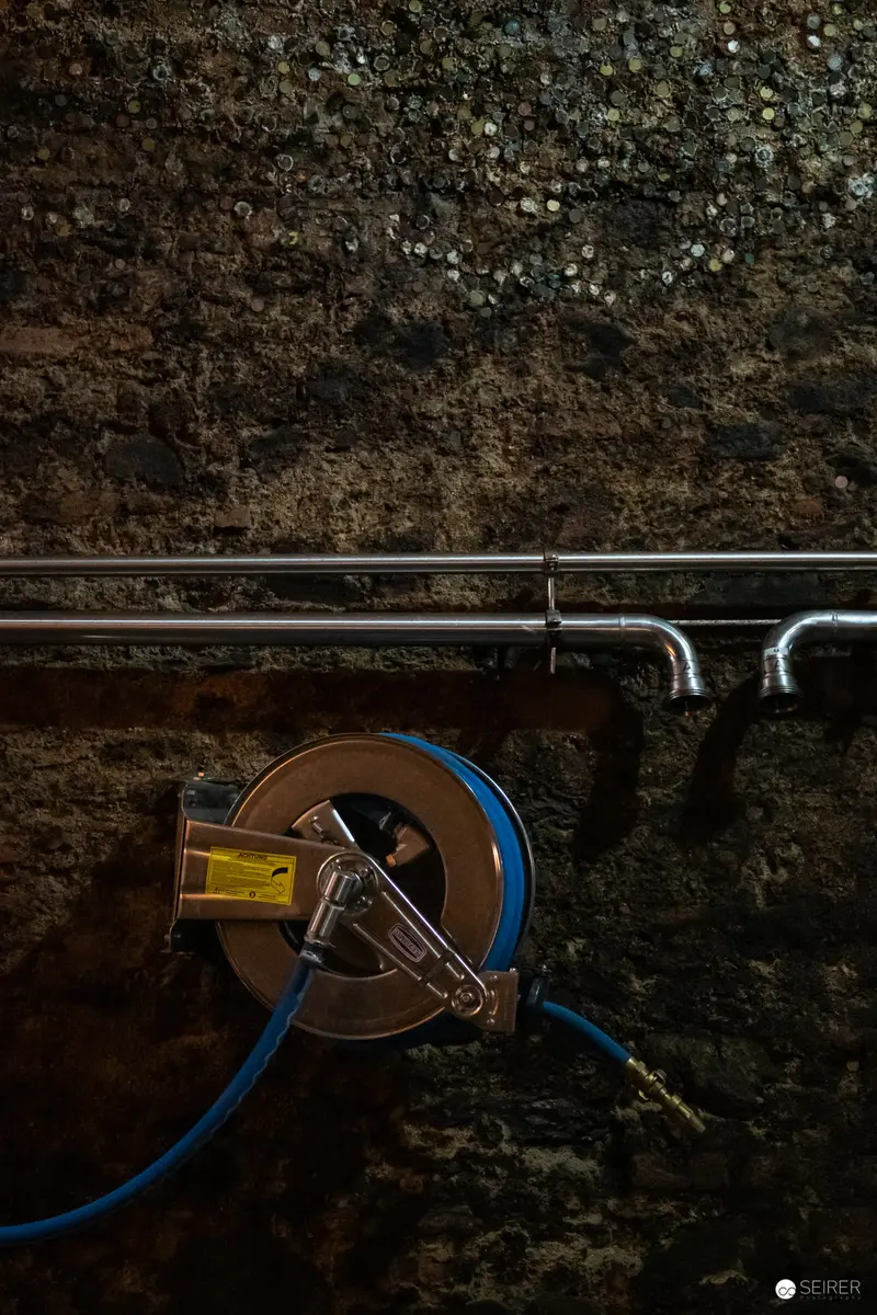 Industrial Utility Hose on Textured Wall at Domäne Wachau Winery Backstage Area