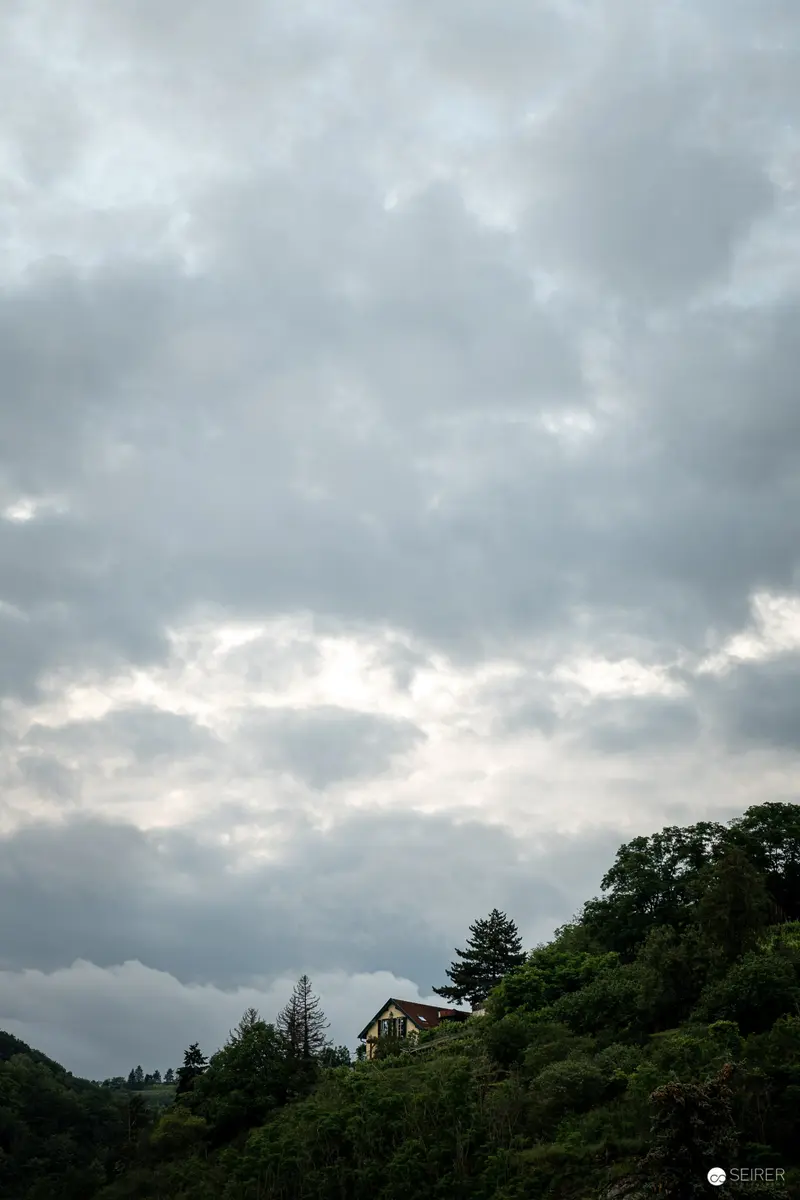 Solitary House on Forested Hillside Under Overcast Sky
