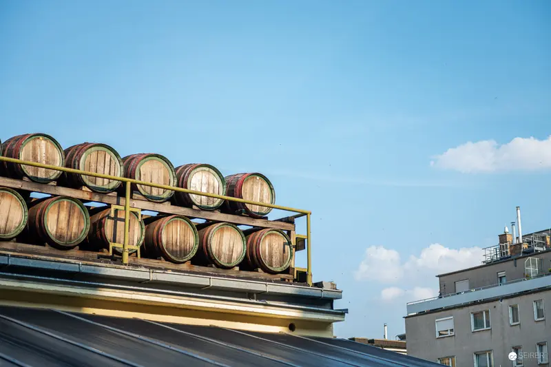 Wooden Wine Barrels Stacked on Urban Rooftop Rack Against Blue Sky