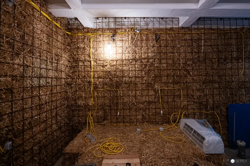 Straw-Lined Utility Space with Exposed Lighting and Yellow Electrical Cord