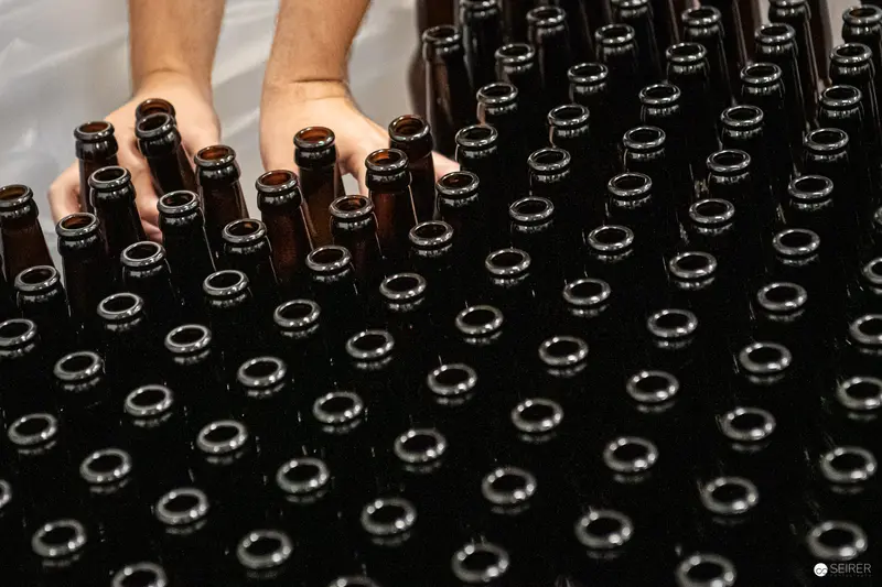 Hands Arranging Brown Glass Bottles at 100 Biere Private Brewery in Vienna