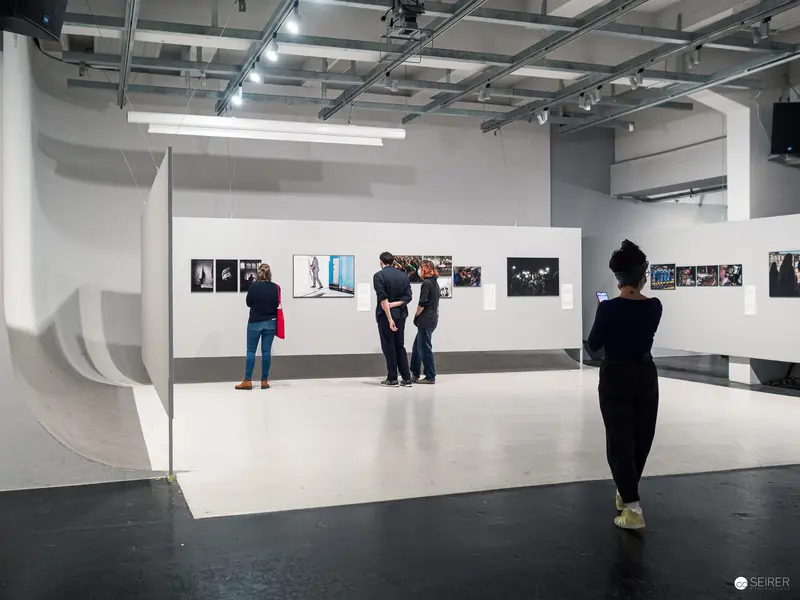 Gallery Visitors Exploring Contemporary Photographic Exhibition in White Modernist Space
