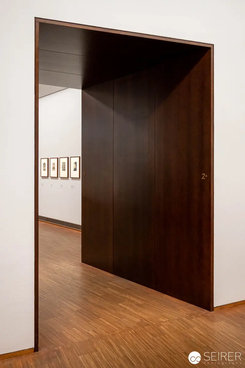 Minimalist Gallery Interior with Dark Wooden Doorway and Framed Artwork