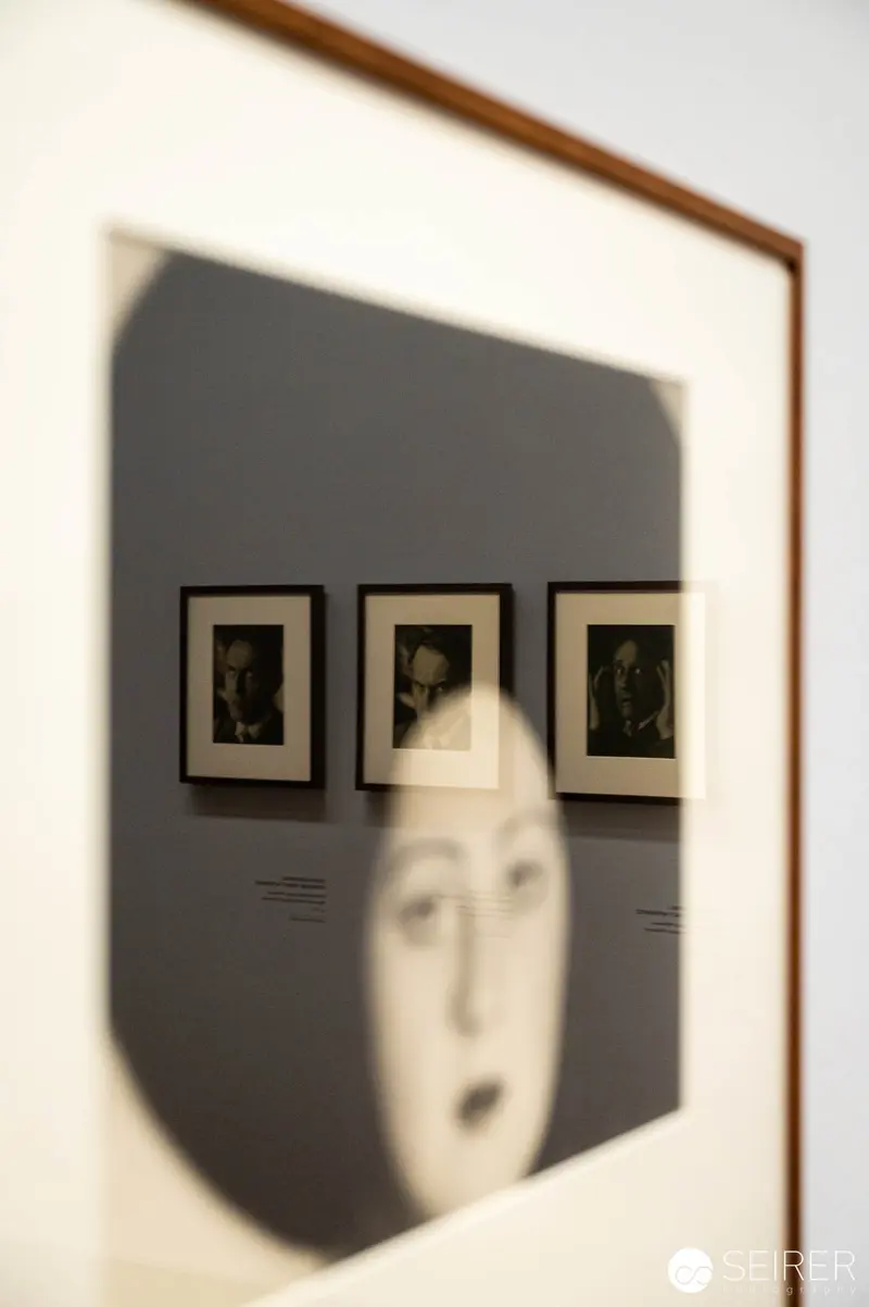 Reflective Framing: Distorted Portrait Amid Gallery Photographs