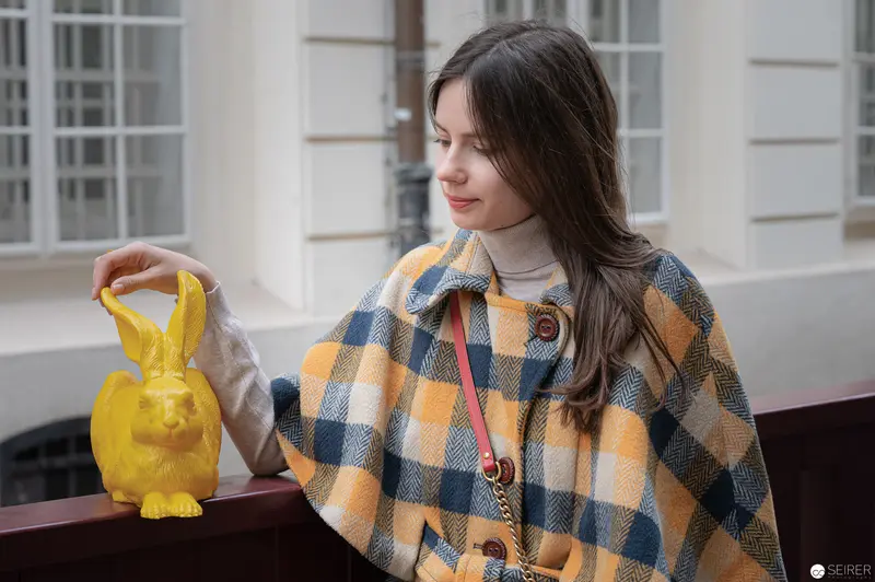 Young Woman with Yellow Ceramic Hare Near Architectural Backdrop