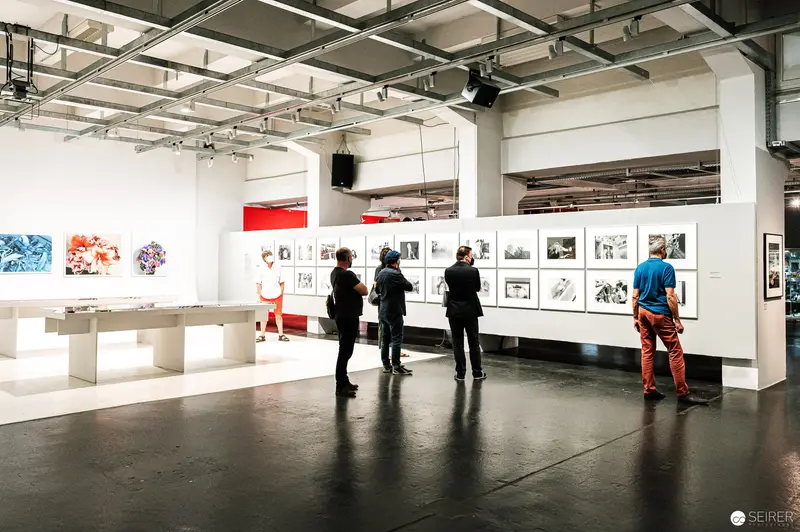 Visitors Examining Photographic Exhibits at Art Gallery Installation
