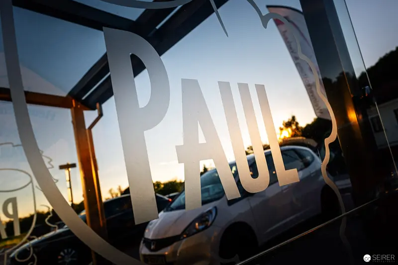 Reflective Storefront Window with 'PAUL' Text at Sunset