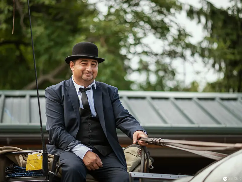 Elegantly Attired Gentleman in Vintage Bowler Hat Aboard Outdoor Setting