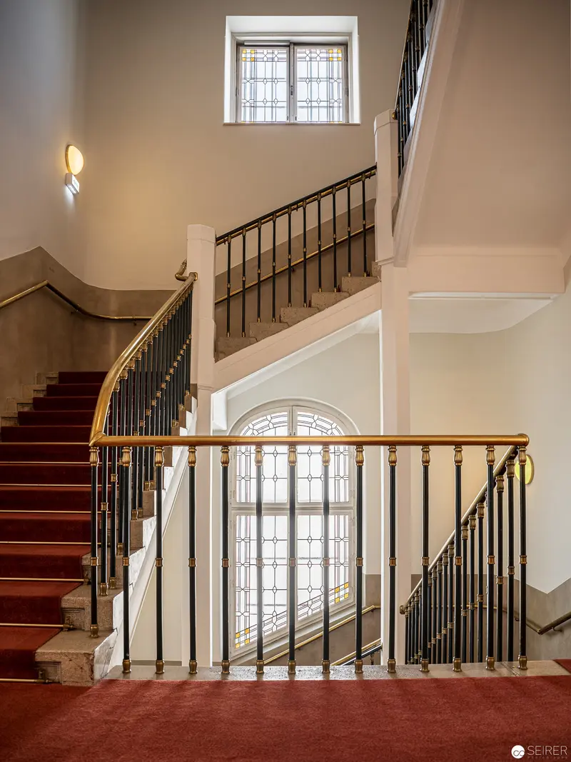 Elegant Staircase Interior with Red Carpet and Ornate Metalwork Railings