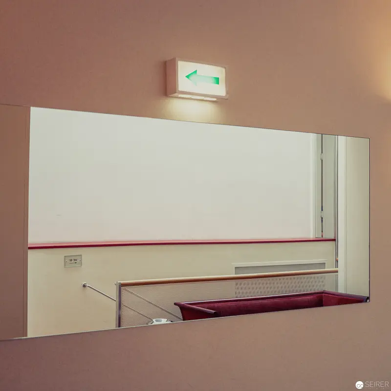 Minimalist Interior with Illuminated Exit Sign and Reflective Surface