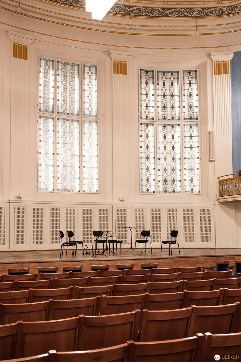Empty Concert Hall with Ornate Windows and Wooden Chairs at Konzerthaus Wien
