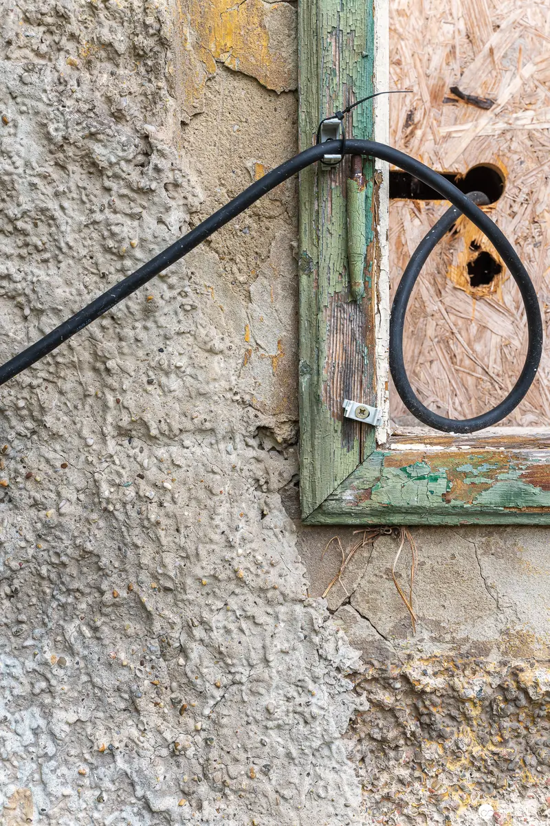 Weathered Green Shutter with Rustic Wrought Iron Hook on Textured Wall