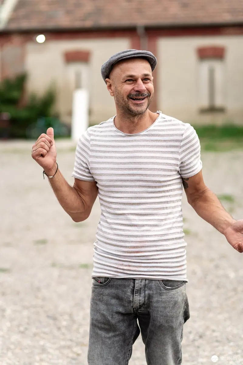 Jubilant Man in Striped Shirt Giving Thumbs Up at Rothneusiedl Farmyard