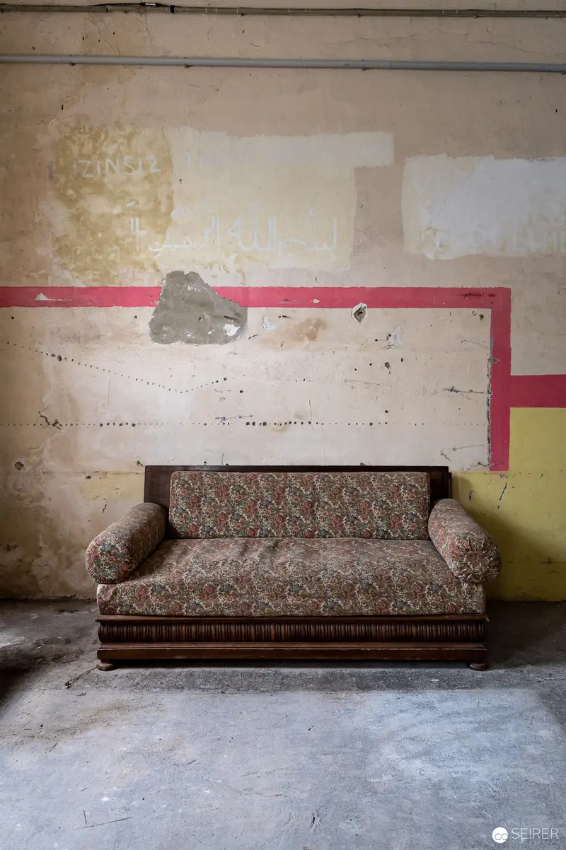 Abandoned Vintage Floral Sofa in Dilapidated Interior with Geometric Wall Accents