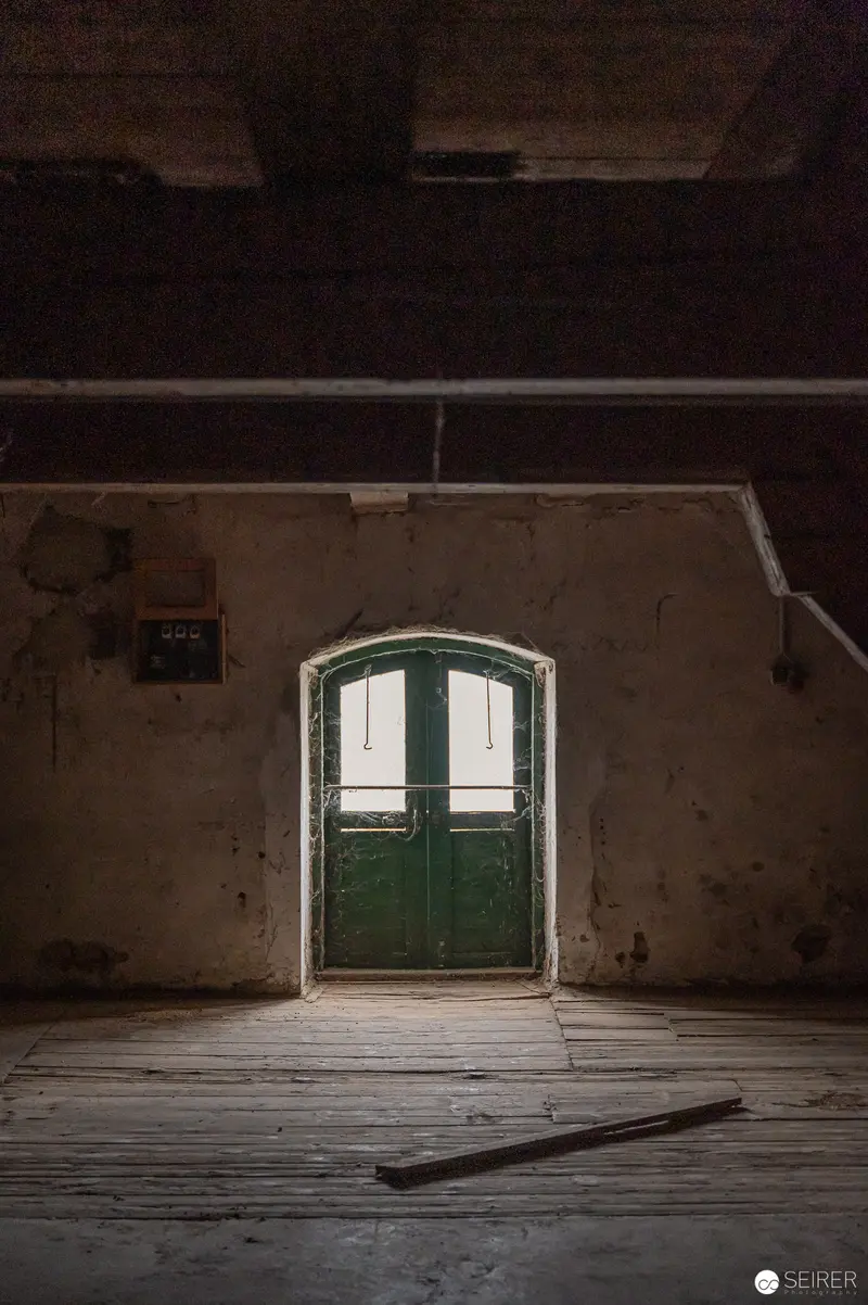 Abandoned Interior with Green Arched Door in Decaying Wooden Space