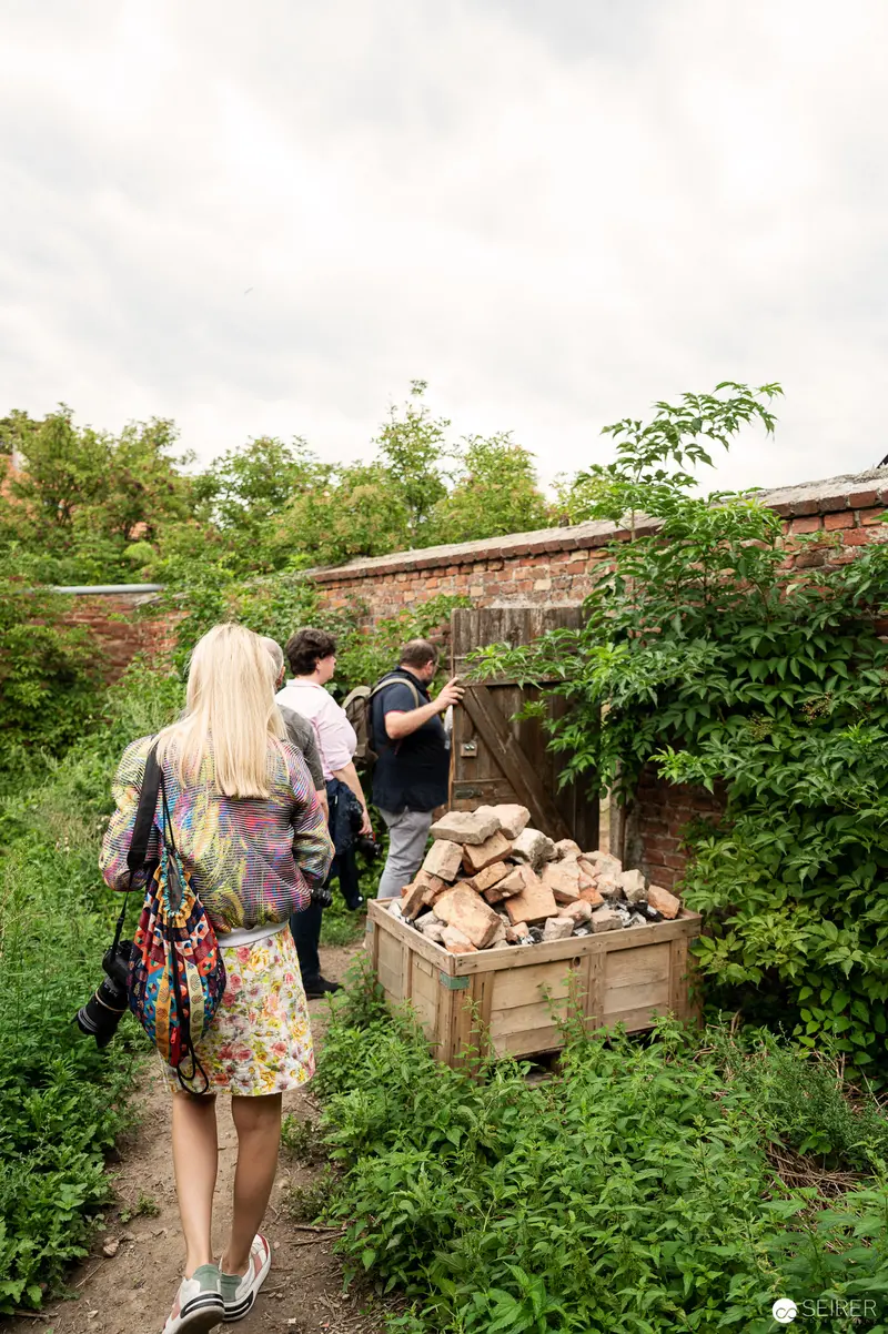 Exploring Rothneusiedl Community Garden with Visitors Examining Wooden Produce Crate