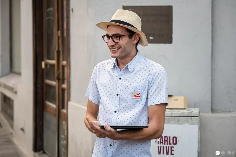 Smiling Young Man in Summer Attire Holding Tablet During Vienna Walking Tour