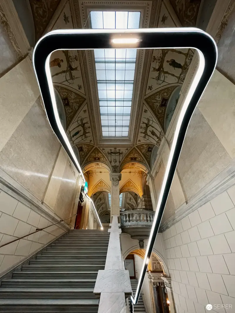 Architectural Perspectives: Curved Handrail Illuminating Ornate Museum Staircase Interior