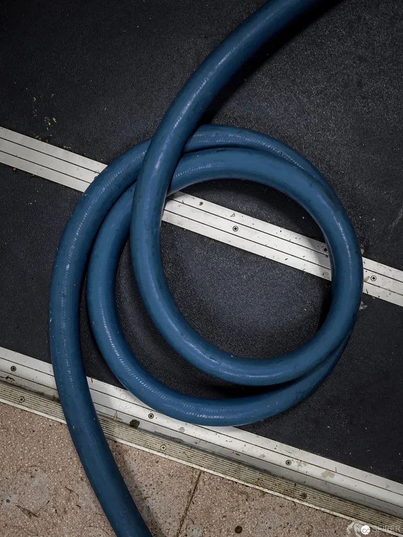 Blue Industrial Hose Coiled on Textured Surface with Metal Strips