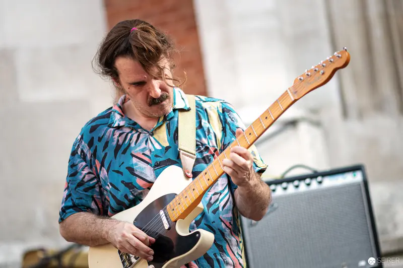 Guitarist in Vibrant Blue Shirt Performing at Musik Befreit Abschlusskonzert