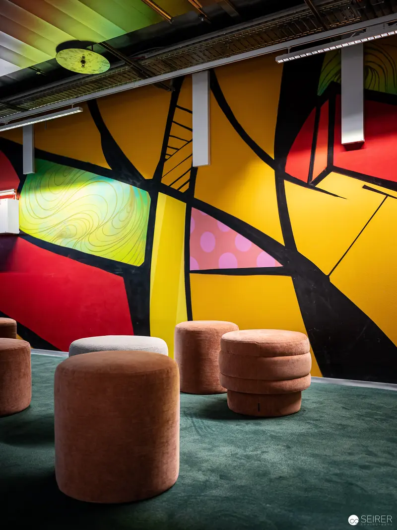 Modernist Lounge Interior with Geometric Wall Mural and Terracotta Seating Pods