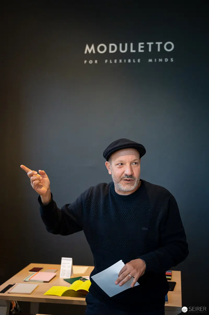 Moduletto Design Week Presenter Gesturing with Emphatic Hand Movement