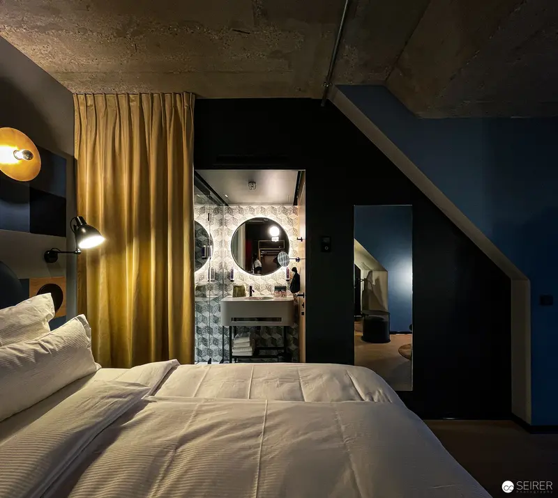 Intimate Hotel Room with Golden Curtain and Minimalist Bathroom Alcove