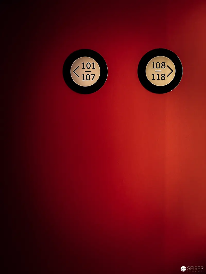 Two Illuminated Indicator Panels on Crimson Background at Hotel Jaz Rooftop Bar