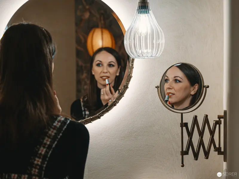 Reflective Moments at Hotel Motto: Woman Applying Lipstick in Dual Mirrors