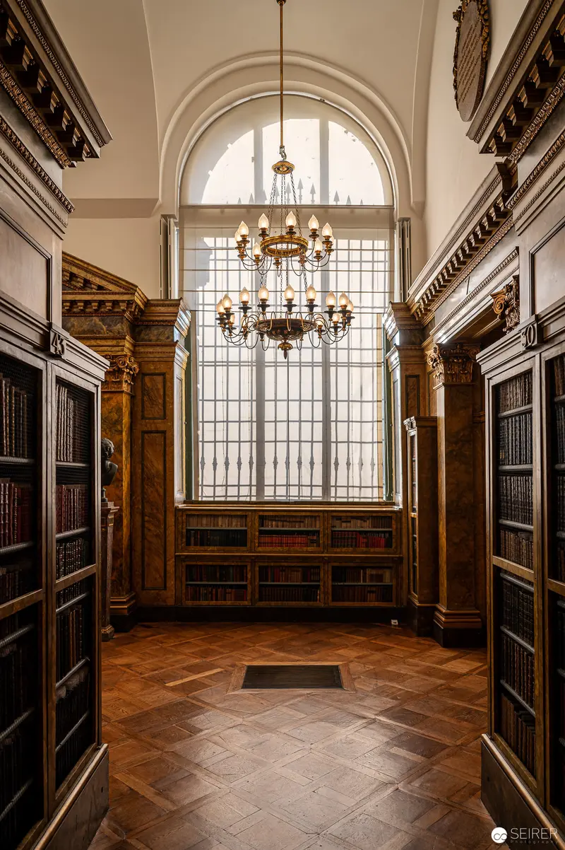 Ornate Library Interior with Arched Window and Baroque Chandelier
