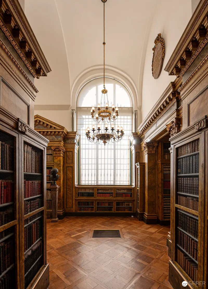 Ornate Library Interior with Arched Window and Antique Bookshelves