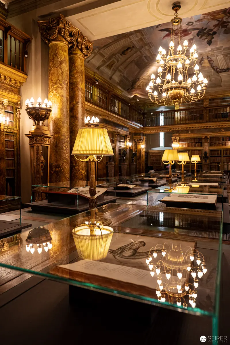 Ornate Library Interior with Illuminated Glass Display Cases and Baroque Chandelier