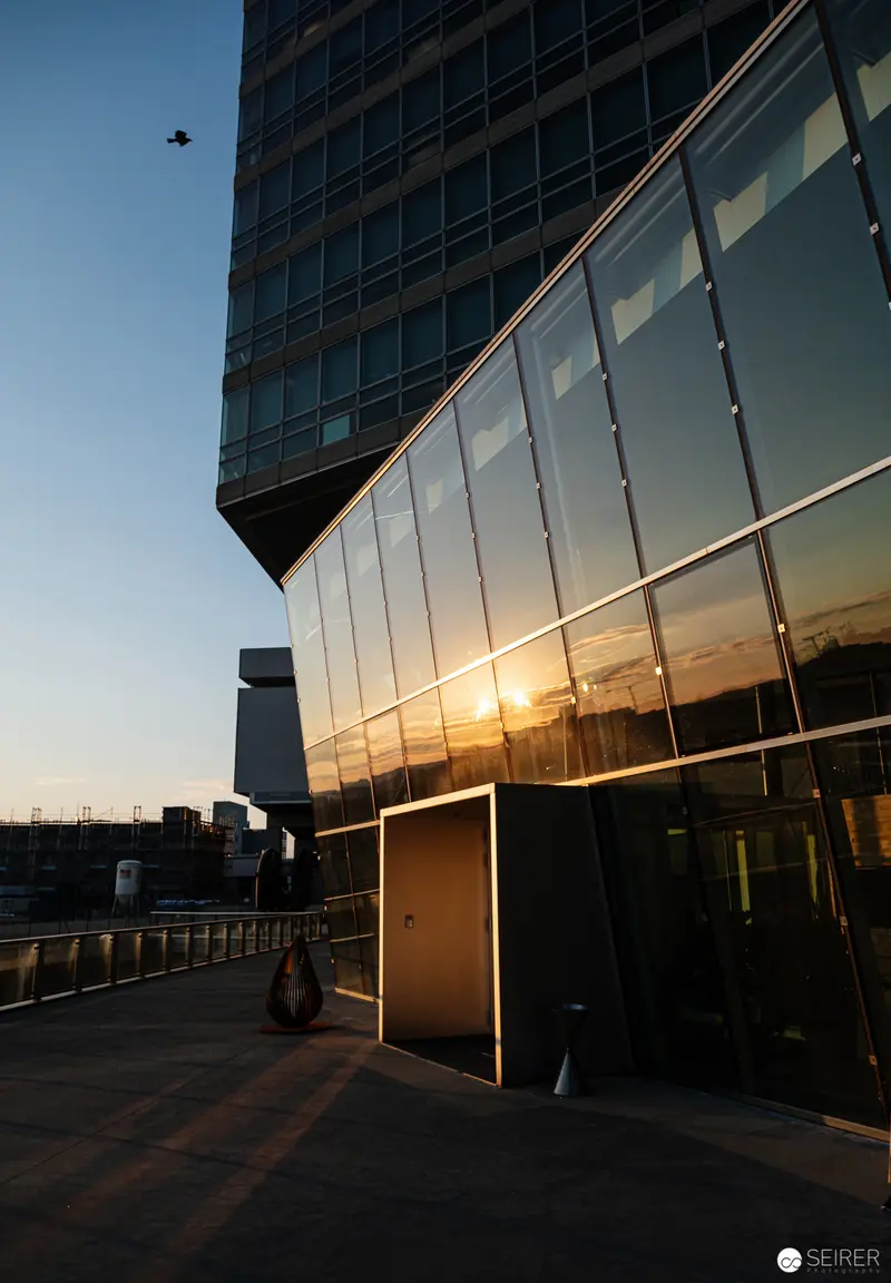 Modern Glass Architecture at Sunset with Reflective Facade and Urban Skyline