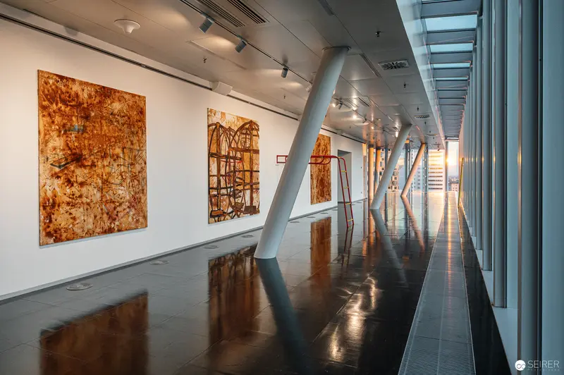 Reflective Gallery Interior with Rust-Toned Abstract Paintings and Architectural Light