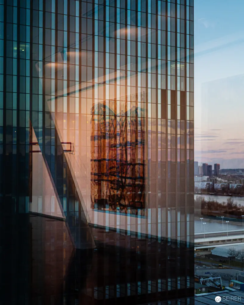 Architectural Reflection: Glass Tower Reveals Urban Landscape at Twilight