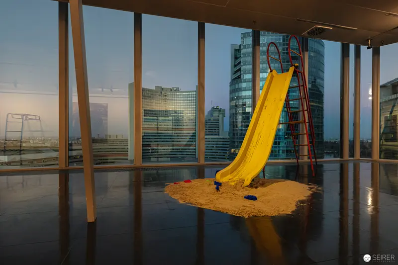 Urban Interior Landscape with Yellow Playground Slide Against Modern Cityscape