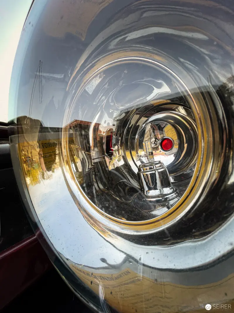 Distorted Reflection in Polished Vehicle Wheel Hub with Red Accent