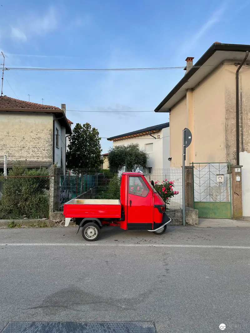 Red Piaggio Ape Utility Vehicle Parked in Residential Italian Street Scene